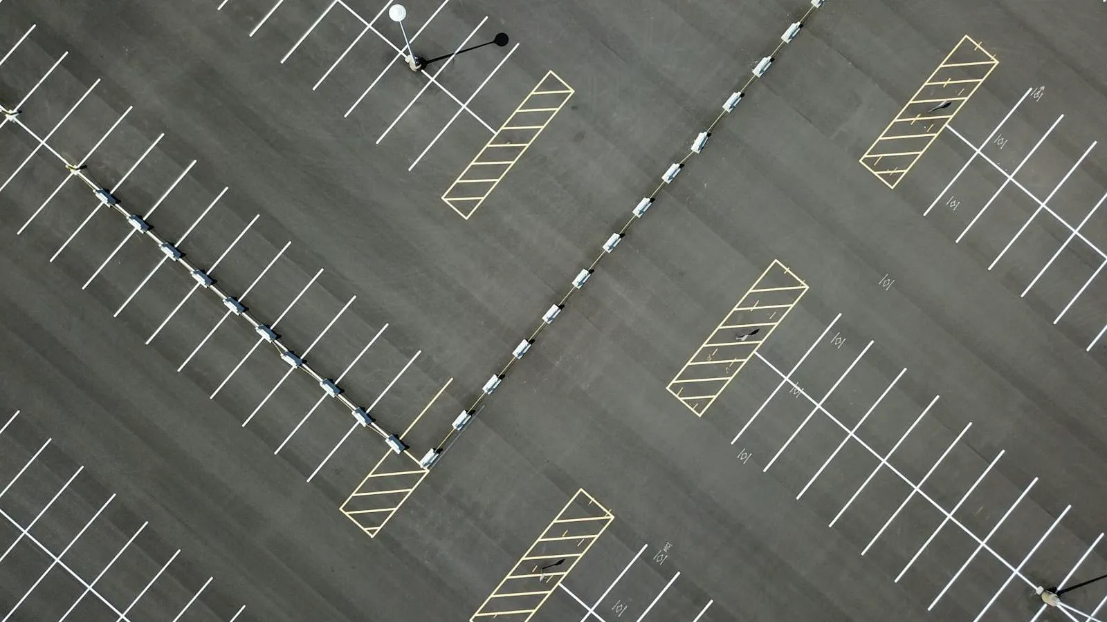 Aerial view of a freshly striped parking lot with white stalls and hatched islands
