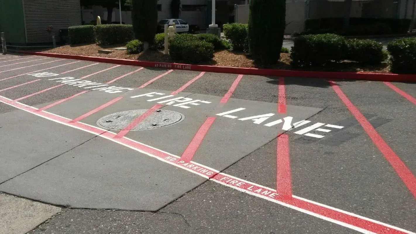 Red painted fire lane with NO PARKING FIRE LANE stencil and hatched markings in front of a building