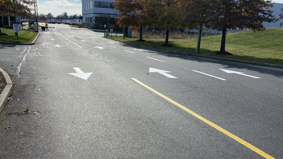 Fresh STOP bar and directional arrows painted on a commercial drive aisle in Connecticut